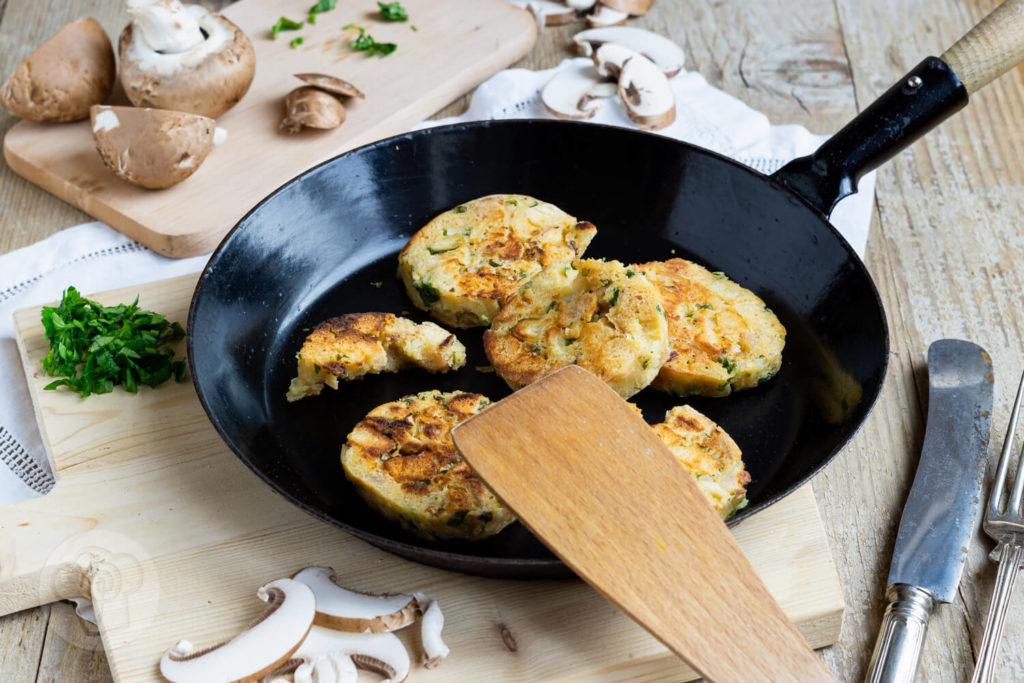 Serviettenknödel mit Pilzsoße und frischen Kräutern. Serviert in einer Pfanne.