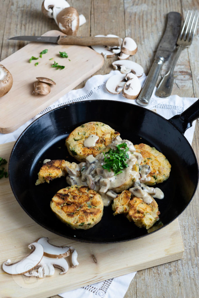 Serviettenknödel mit Pilzsoße und frischen Kräutern. Serviert in einer Pfanne.