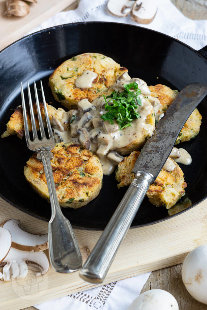 Serviettenknödel mit Pilzsoße und frischen Kräutern. Serviert in einer Pfanne.