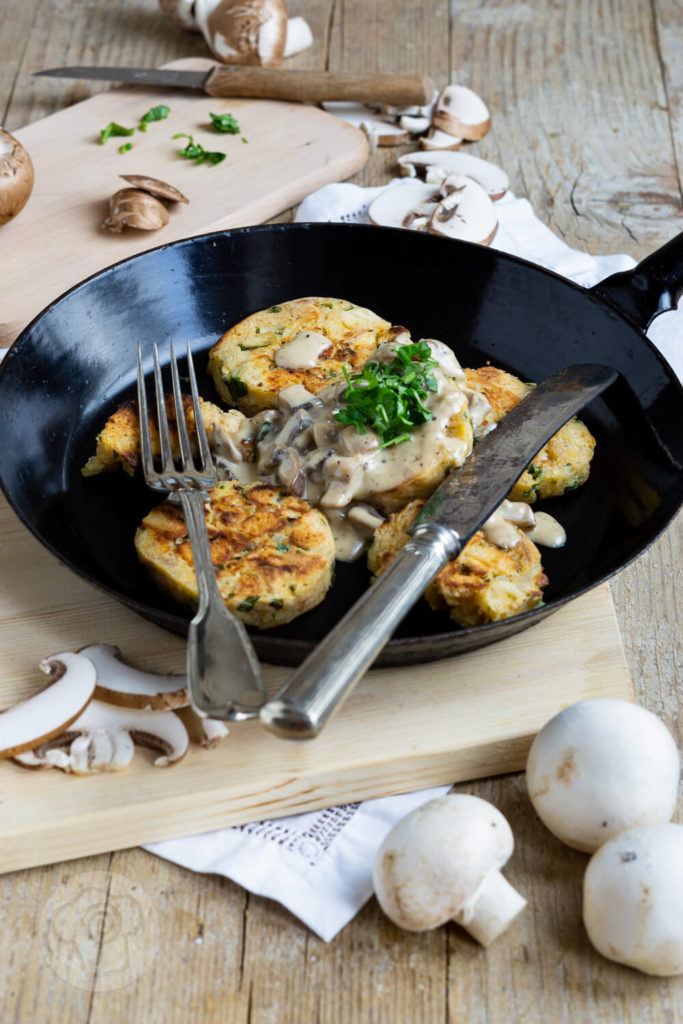 Serviettenknödel mit Pilzsoße und frischen Kräutern. Serviert in einer Pfanne.