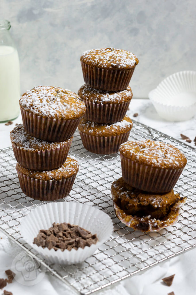 Muffins mit Schokostückchen, gestapelt, bei einem Muffin Papier halb entfernt