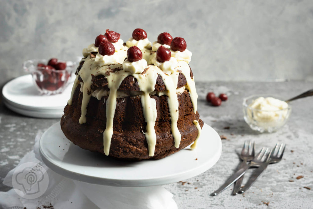 Rezept zum Backen. Schwarzwälder Kirsch Gugelhupf. Eine Neuinterpretation der klasischen Schwarzwälder Kirsch Torte. Probiert doch diesen einfachen und leckeren Kuchen mit Kirschen und weißer Schokoglasur einfach aus. Küchentraum & Purzelbaum