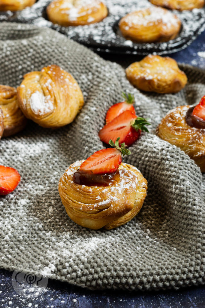 Cruffins mit Puderzucker, Erdbeermarmelade und einer Erdbeerhälfte