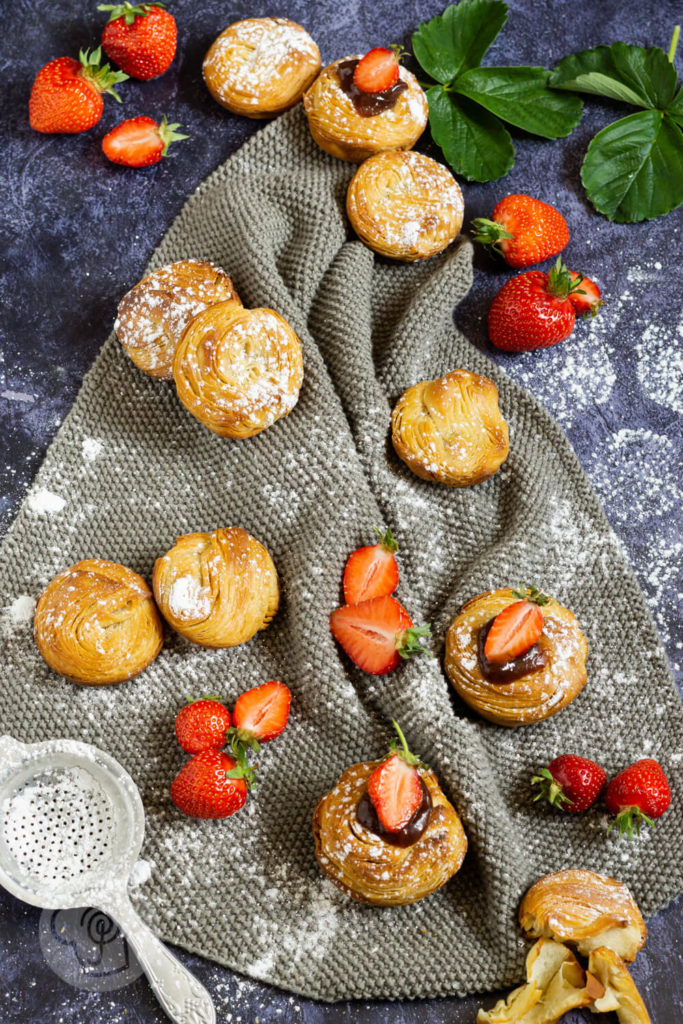 Cruffins von oben mit Puderzuckersieb, Erdbeeren und Marmelade