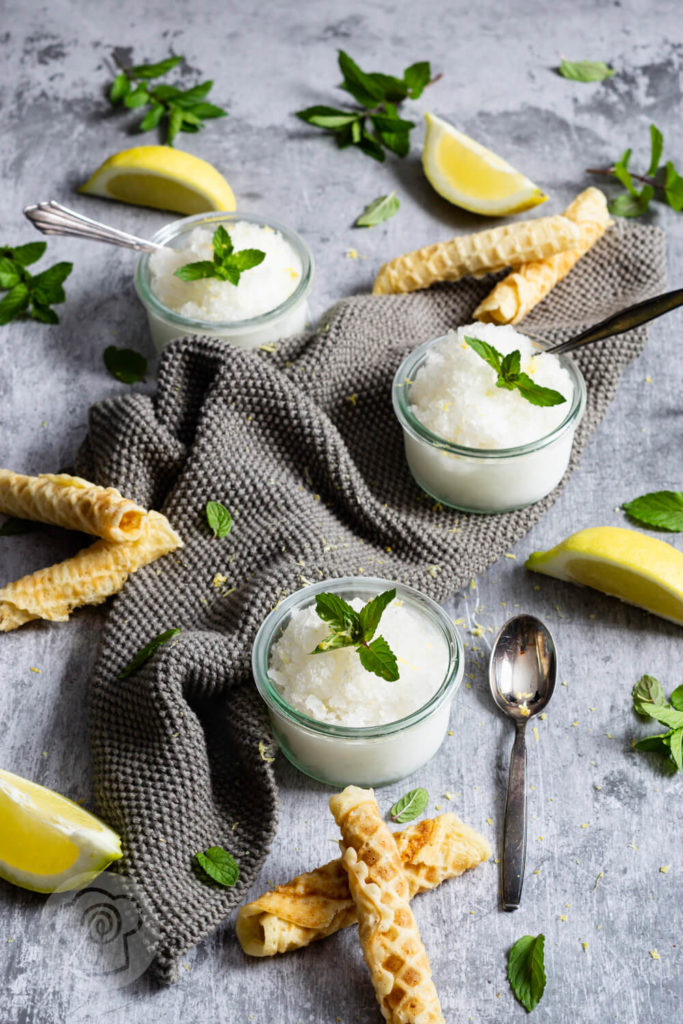 3 Gläser Zitronen Granita mit Zitronenvierteln, Minze und Waffeln