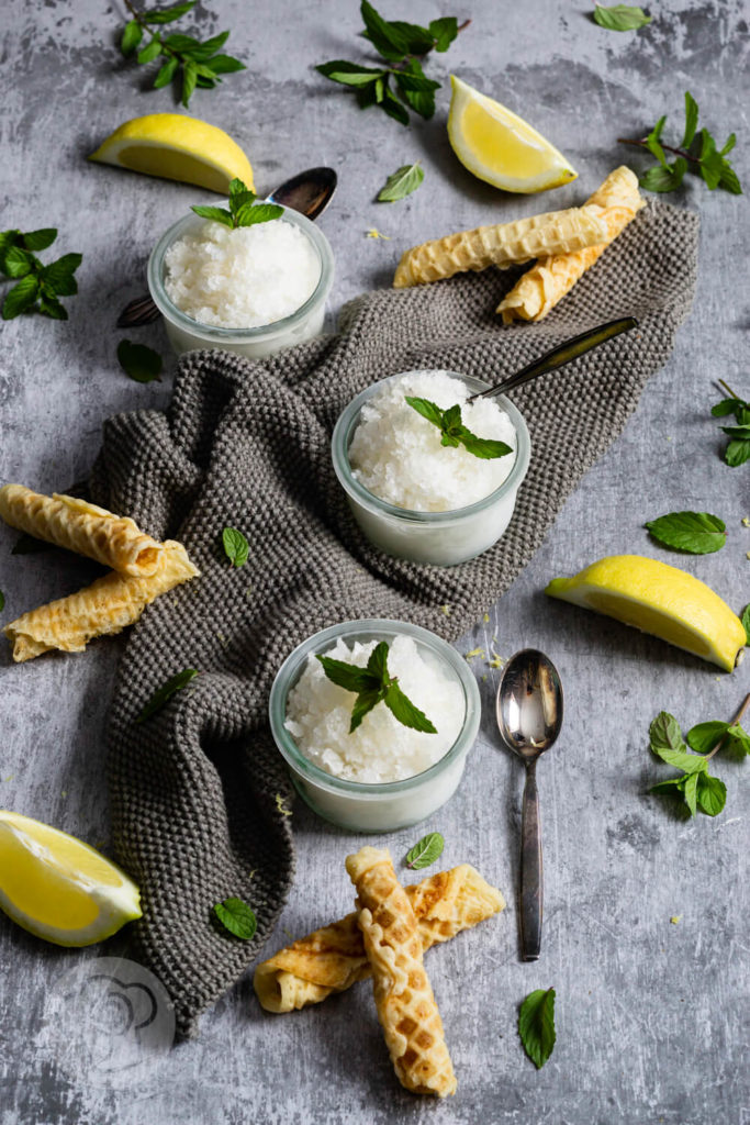 3 Gläser Zitronen Granita mit Zitronenvierteln, Minze und Waffeln