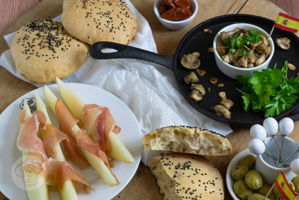 Gebratene Knoblauch Champignons mit Petersilie und Fladenbrot. Tapas serviert in einer gusseisernen Pfanne.