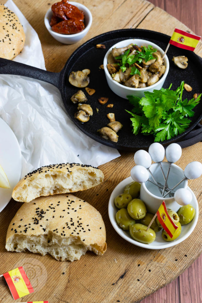 Gebratene Knoblauch Champignons mit Petersilie und Fladenbrot. Tapas serviert in einer gusseisernen Pfanne.