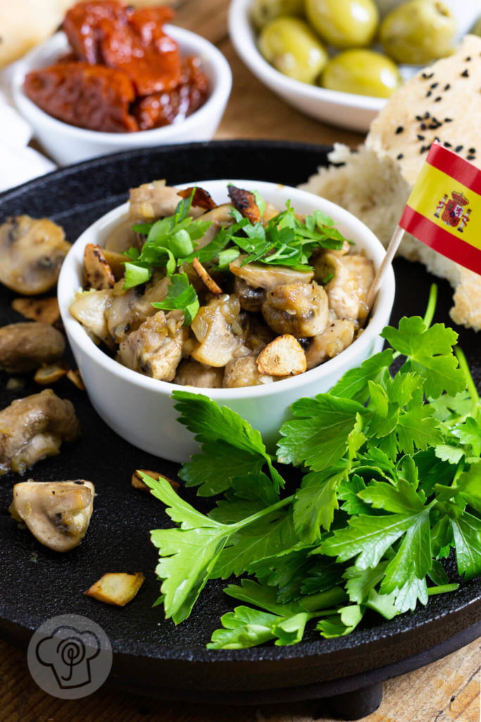 Gebratene Knoblauch Champignons mit Petersilie und Fladenbrot. Tapas serviert in einer gusseisernen Pfanne.