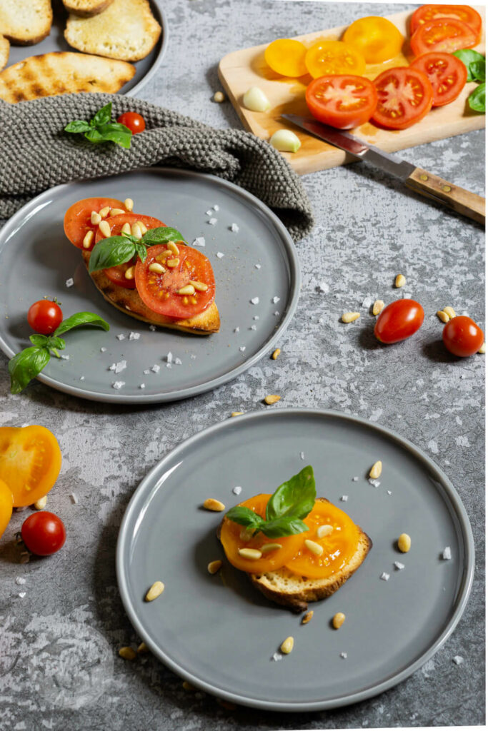 Geröstetes Brot mit Tomaten, Pinienkernen und Basilikum auf einem Teller