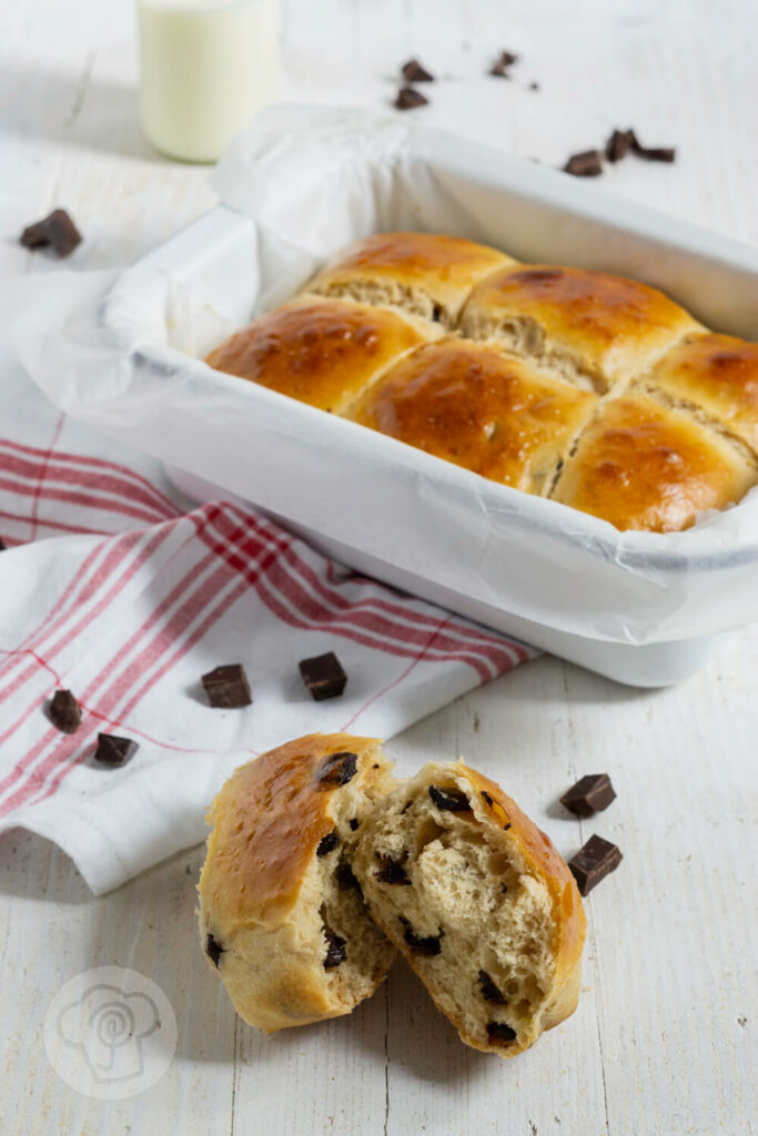 Dänische Schokobrötchen aus Hefeteig aufgebrochen. Im Hintergrund noch mehr Brötchen in der Auflaufform.