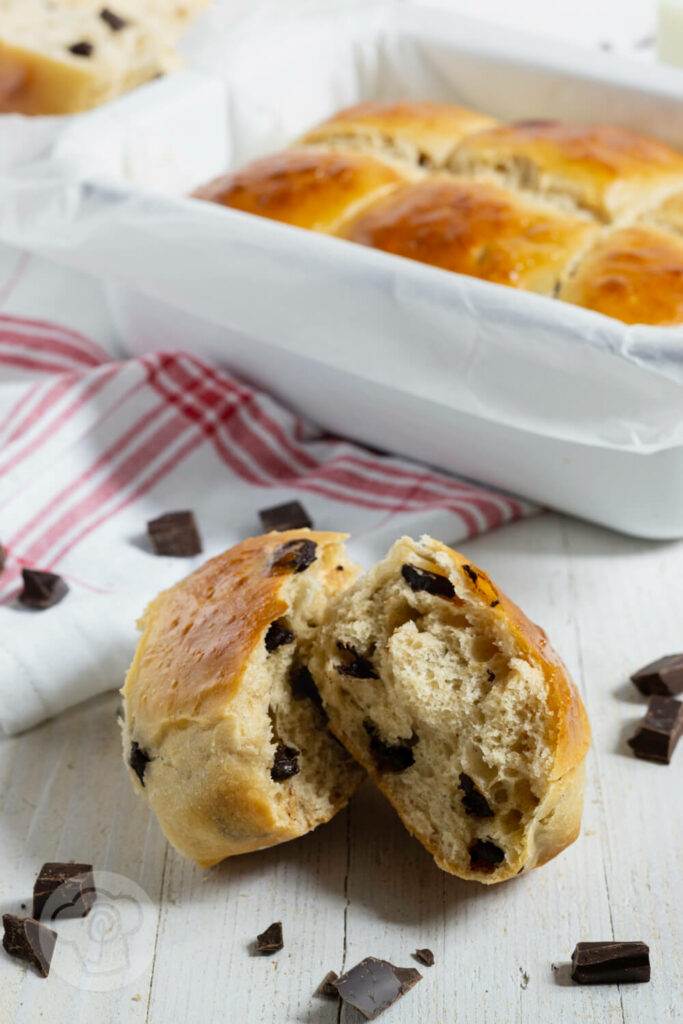 Dänische Schokobrötchen aus Hefeteig aufgebrochen. Im Hintergrund noch mehr Brötchen in der Auflaufform.