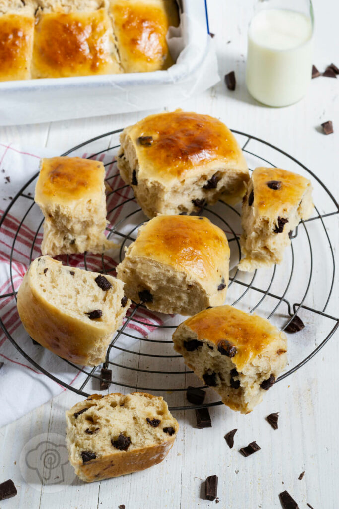 Dänische Schokobrötchen aus Hefeteig auf einem Rost. Im Hintergrund eine Flasche Milch und noch mehr Brötchen.