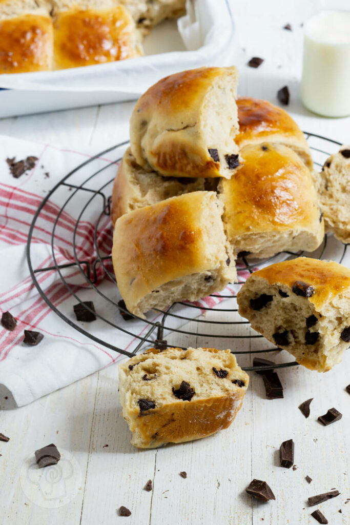 Dänische Schokobrötchen aus Hefeteig auf einem Rost. Im Hintergrund eine Flasche Milch und noch mehr Brötchen.