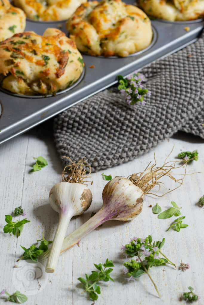 Kräuter Zupfbrot Muffins 3 Knoblauch im Vordergrund, im Hintergrund Muffinblech