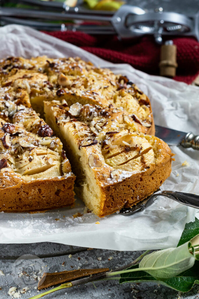 Einfacher gedeckter Apfelkuchen mit Nüssen. Ein Stück auf der Kuchenschaufel.