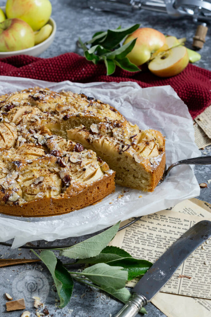 Einfacher gedeckter Apfelkuchen mit Nüssen. Ein Stück auf der Kuchenschaufel.