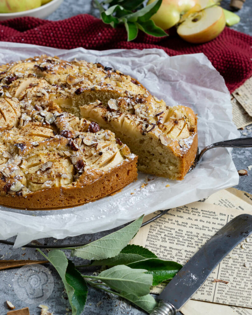 Einfacher gedeckter Apfelkuchen mit Nüssen. Ein Stück auf der Kuchenschaufel.