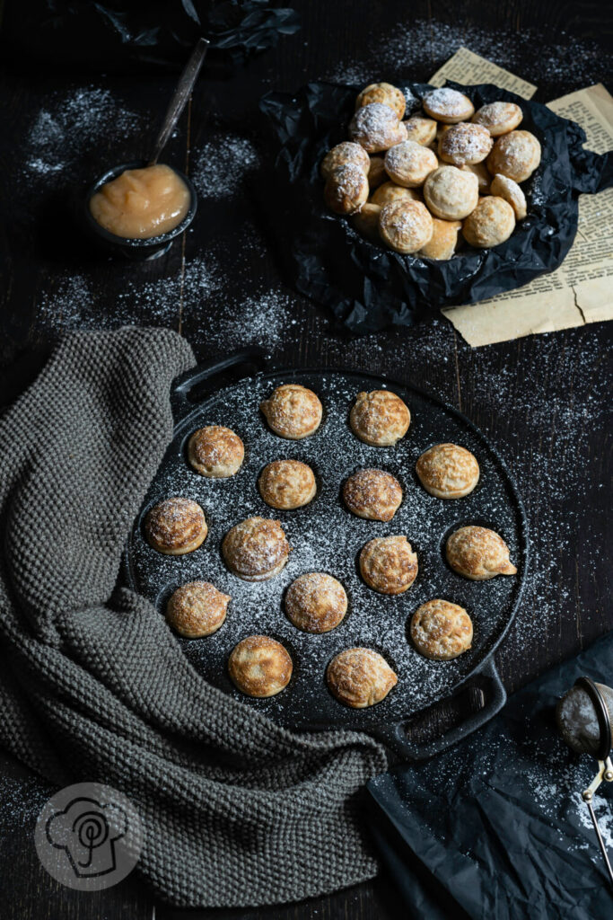 Poffertjes in der Pfanne mit Puderzucker und Apfelbrei.