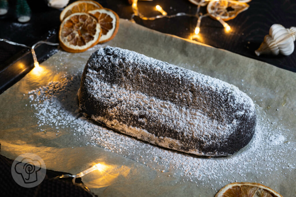 Schoko Stollen mit Orange auf einem Blech mit Backpapier, umgeben von Orangenscheiben und einer Lichterkette.