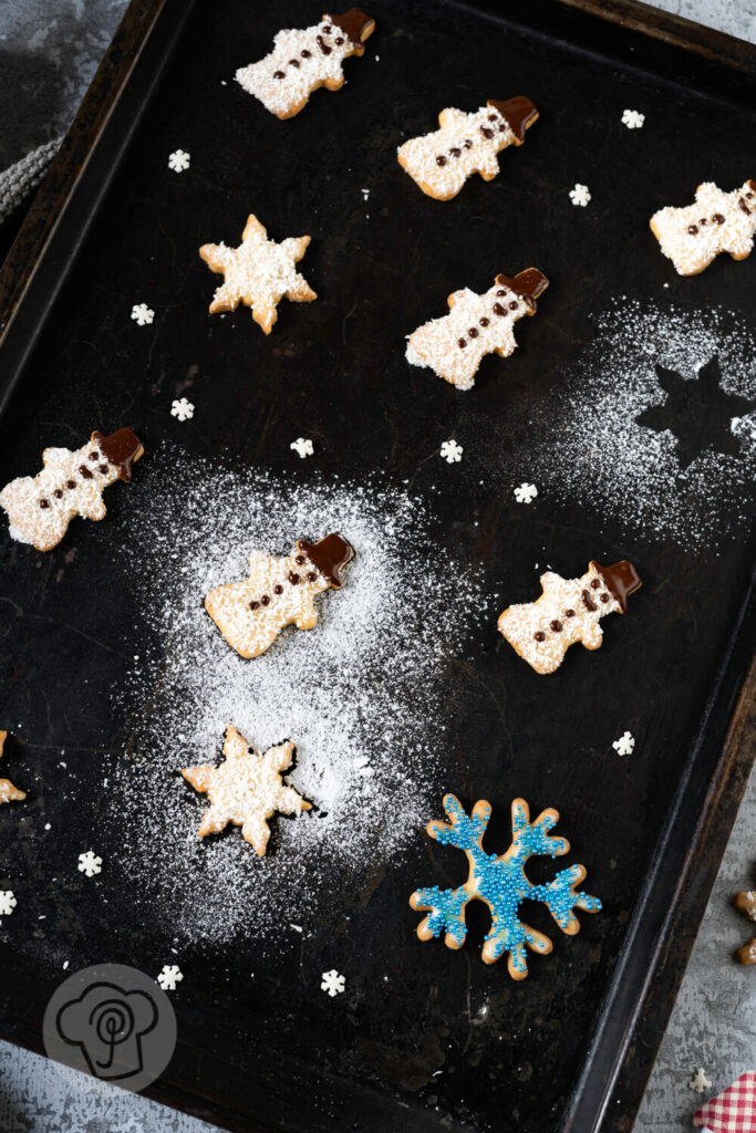 Schneemann Kekse und Schneeflocken auf einem Blech