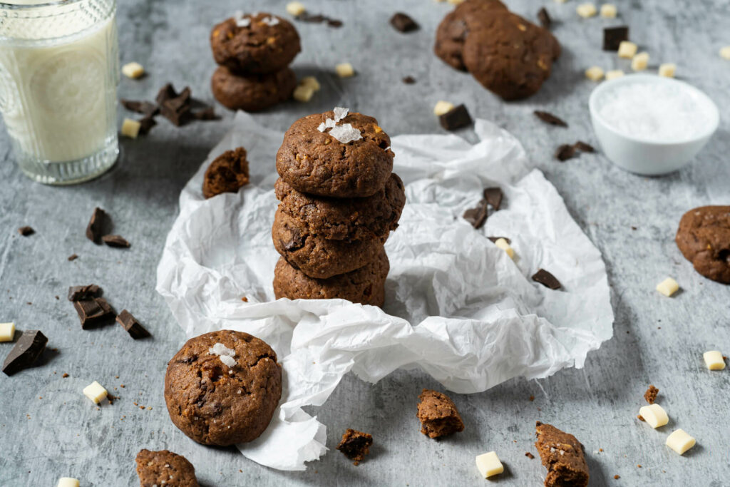 Triple Chocolate Cookies gestapelt, mit Milch und Schokostückchen.