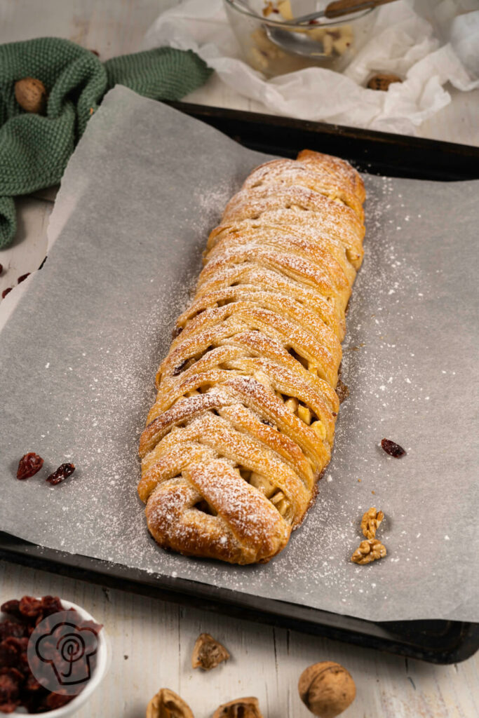 Ukrainischer Apfelzopf mit Blätterteig, Cranberries und Walnüssen auf dem Blech.