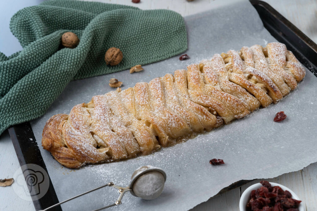 Ukrainischer Apfelzopf mit Blätterteig, Cranberries und Walnüssen auf dem Blech.