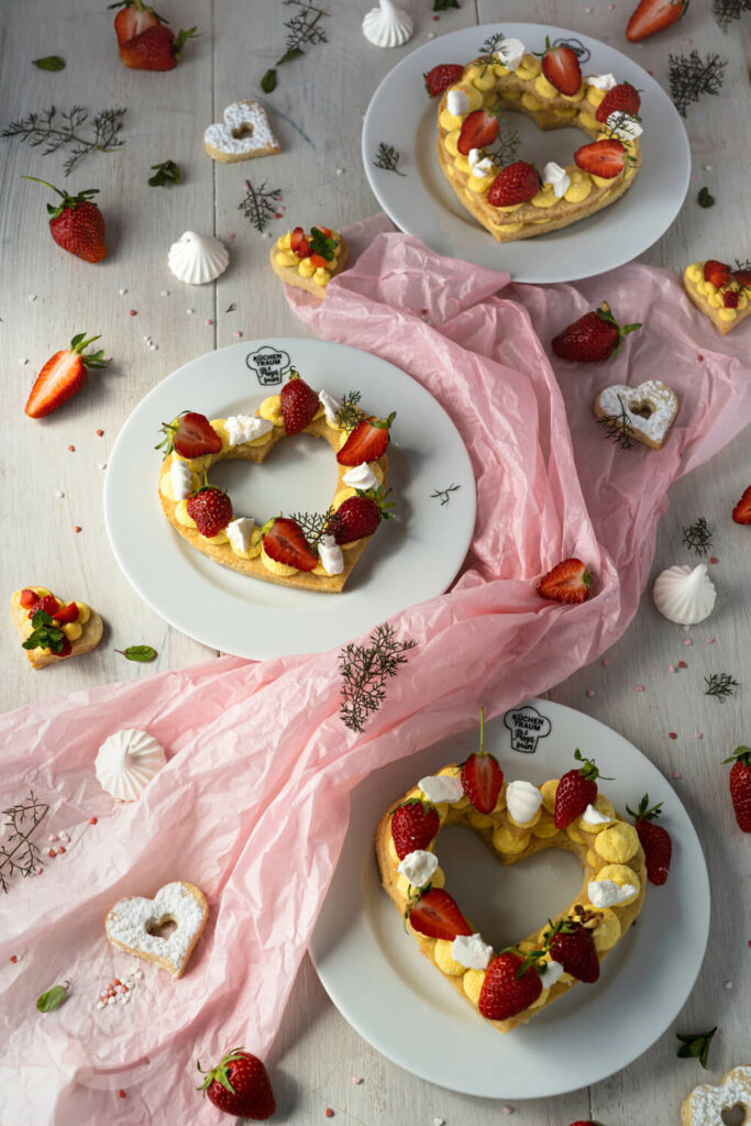 3 Letter Cakes auf Tellern verteilt mit Erdbeeren und Baiser dekoriert
