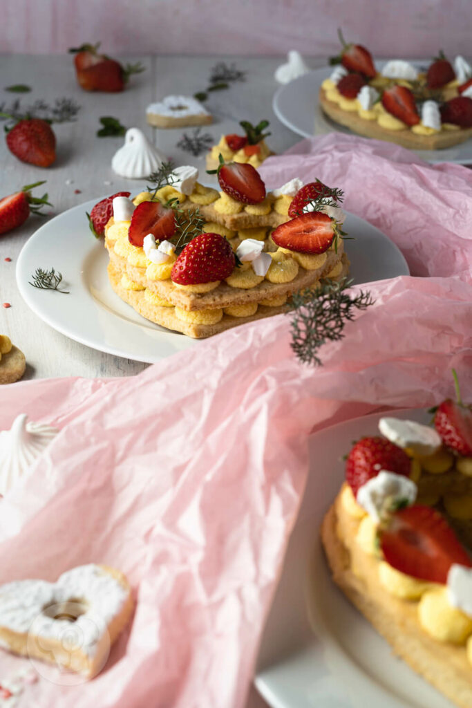 Letter Cakes auf Tellern verteilt mit Erdbeeren und Baiser dekoriert