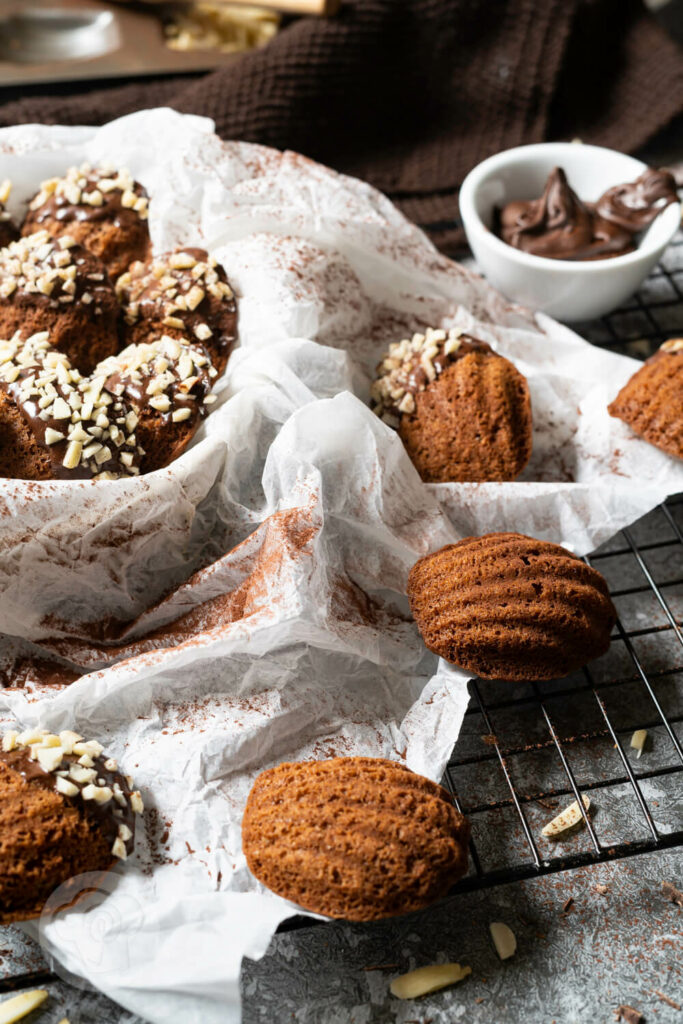 Schokoladen Madeleines teils in einer Schüssel, teils auf einem Rost