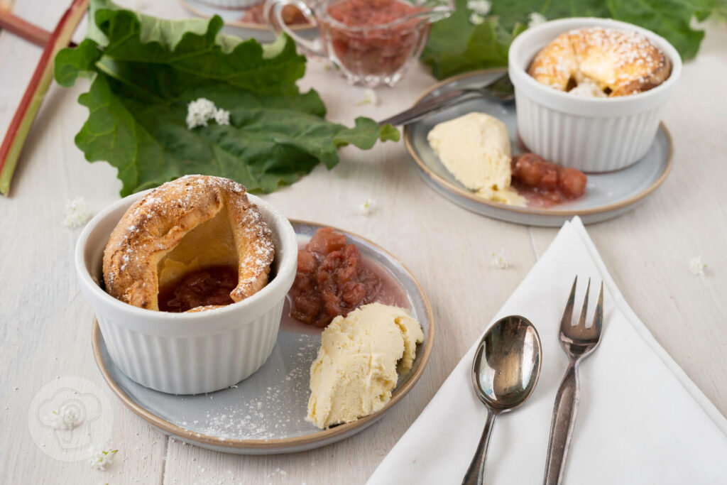 Süßer Yorkshire Pudding mit Rhabarberragout auf einem Teller, dazu Vanilleeis