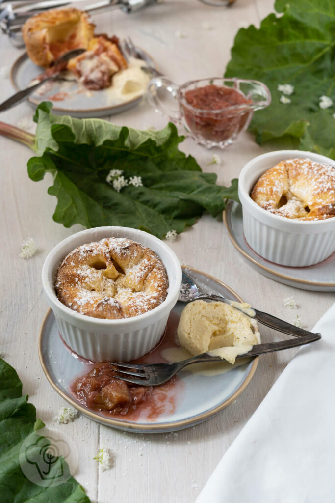 Süßer Yorkshire Pudding mit Rhabarberragout auf einem Teller, dazu Vanilleeis