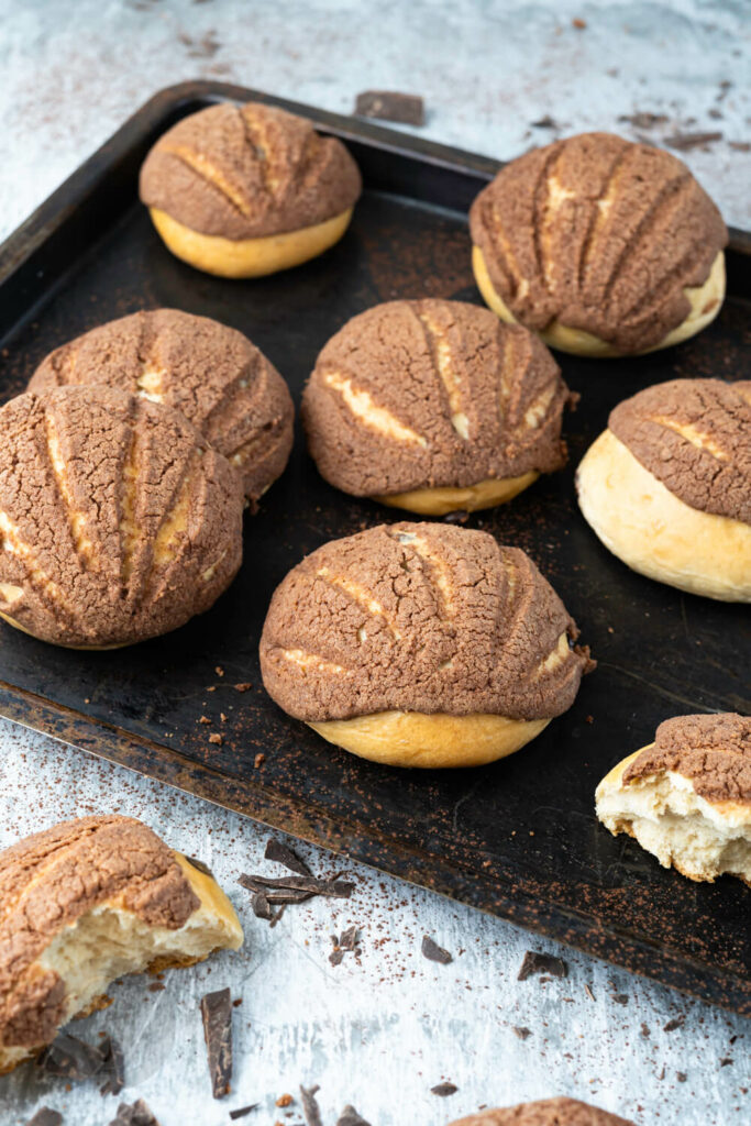 Mexikanische Conchas auf einem Blech mit Schokostückchen.