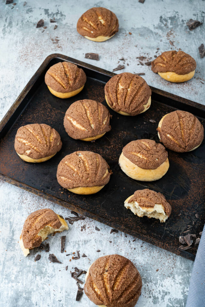 Mexikanische Conchas auf einem Blech mit Schokostückchen.