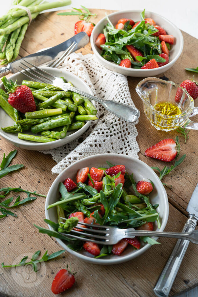 Spargelsalat mit Erdbeeren 2 Spargelsalat mit grünem Spargel, Erdbeeren und Rucola in kleinen Tellern.