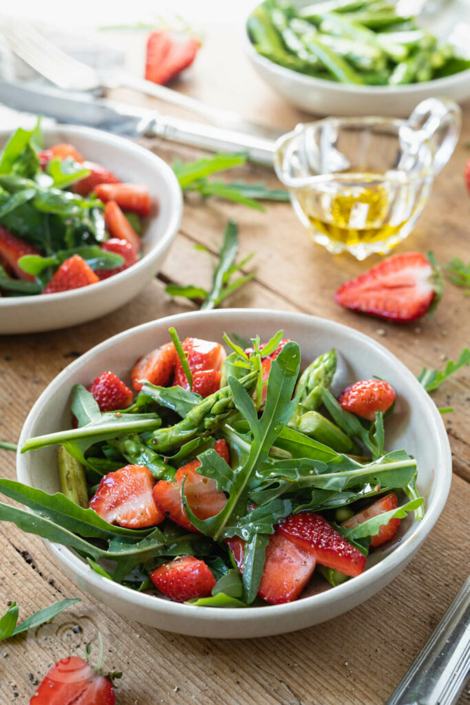 Spargelsalat mit Erdbeeren 4 Spargelsalat mit grünem Spargel, Erdbeeren und Rucola in kleinen Tellern.