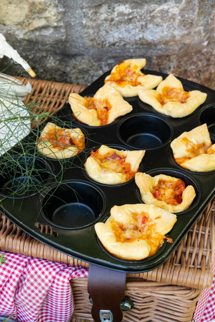 Einfache Pizzamuffins im Muffinblech auf einem Picknickkorb