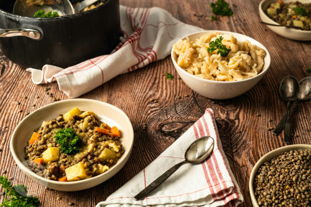 Vegetarischer Linseneintopf mit Spätzle im Topf und im Teller angerichtet