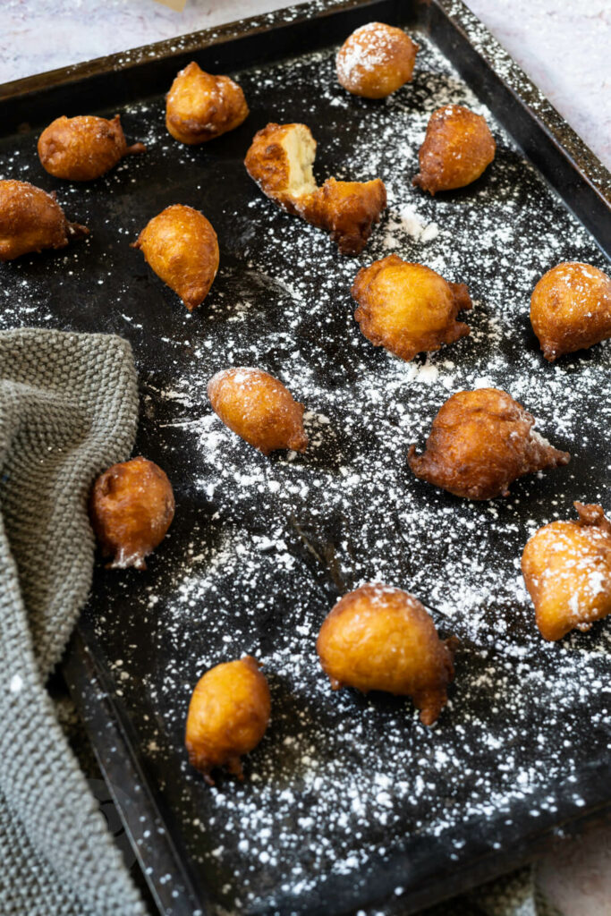 Mikate (Puffpuff, Beignets) mit Puderzucker auf einem Blech