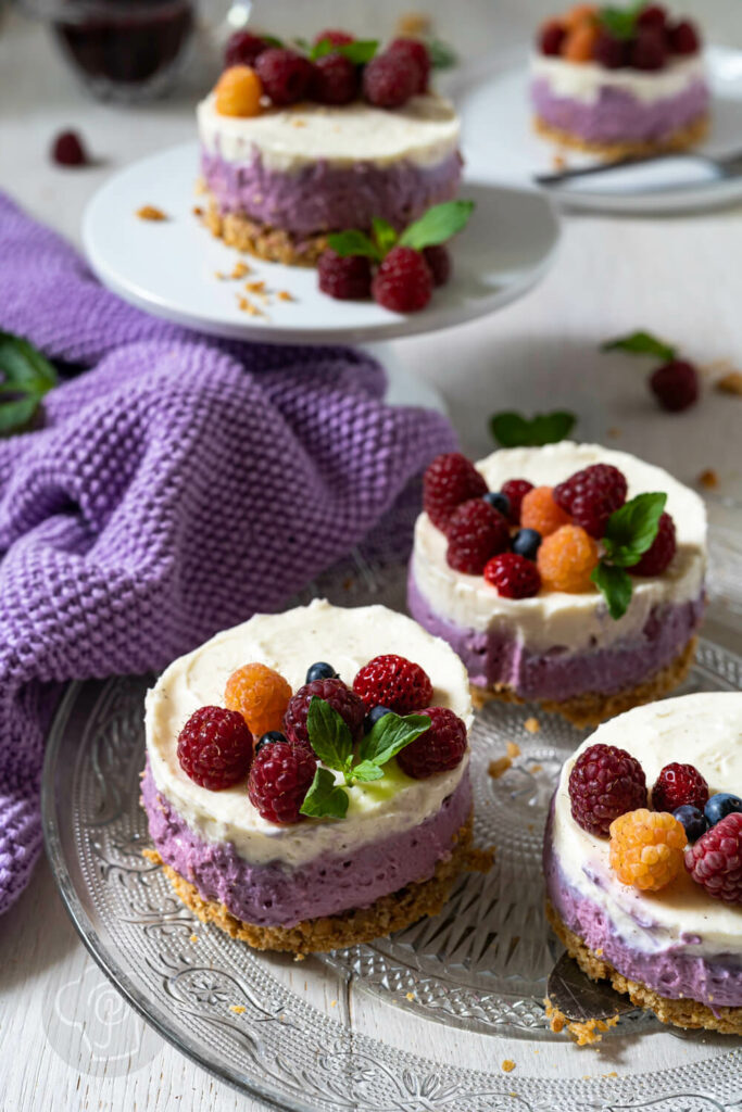 Mini-Cheesecakes mit Beeren auf einer Etagère und auf einem Glasteller