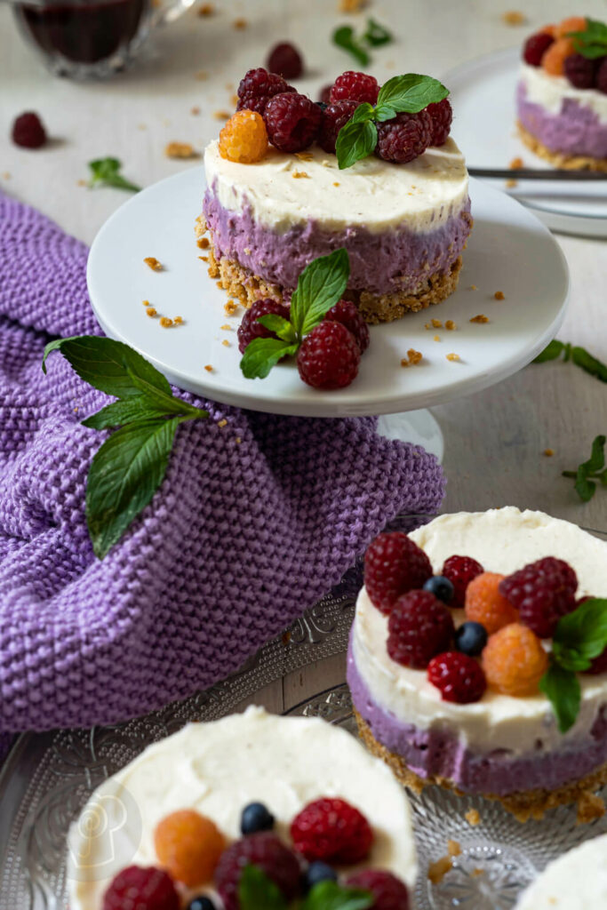 Mini-Cheesecakes mit Beeren auf einer Etagère und auf einem Glasteller