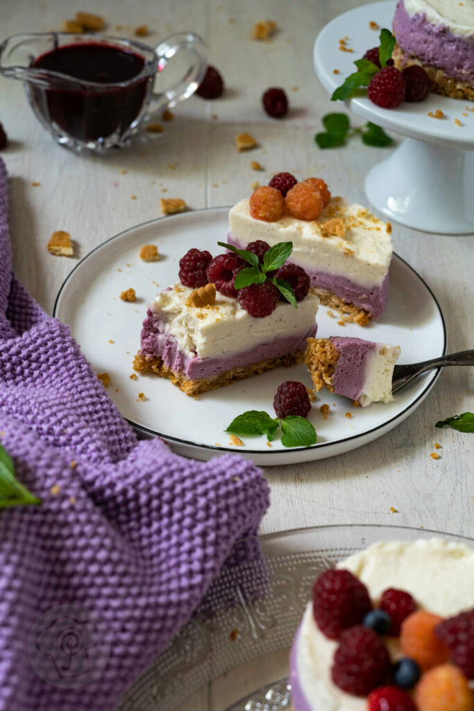 Mini-Cheesecake auseinandergeschnitten auf einem Teller. Dazu Beerenpüree