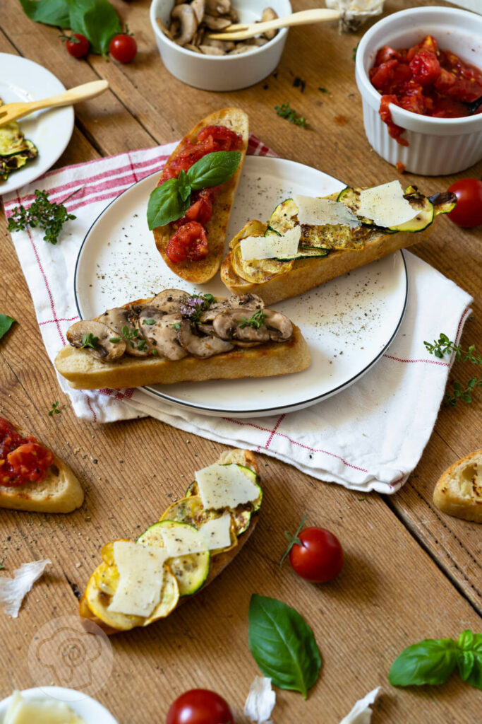 Verschiedene Bruschetta Versionen mit Zucchini und Parmesan, Tomaten, Champignons auf einem Teller