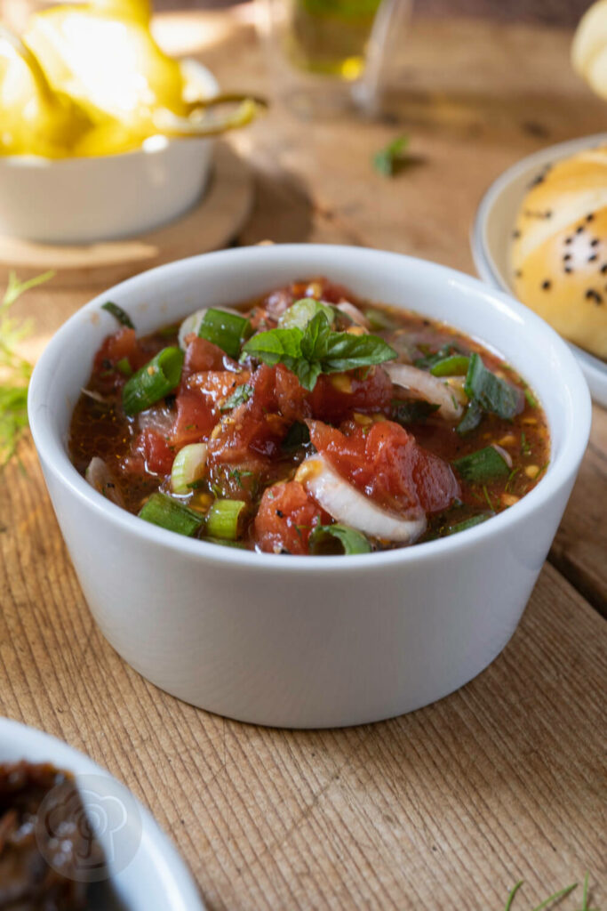 Türkischer Tomatensalat in einer Schüssel. Dazu Tee, Peperoni und getrocknete Tomaten.