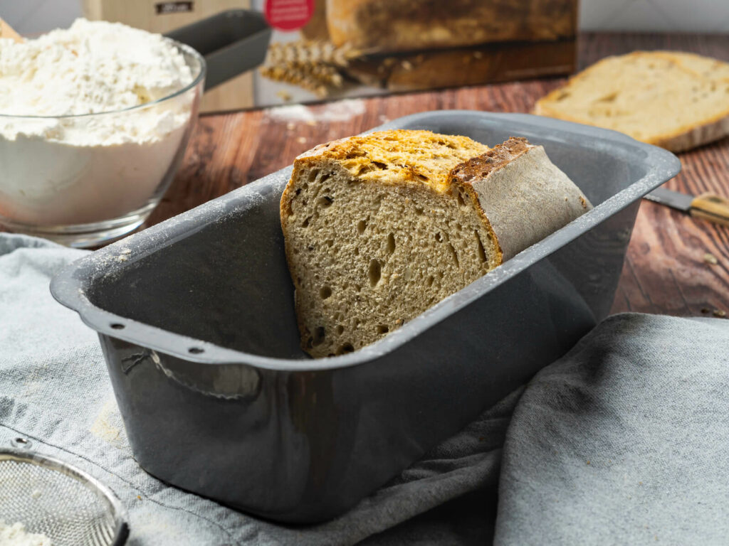 Körnerbrot mit Sauerteig in einer Kastenform. Brot angeschnitten.