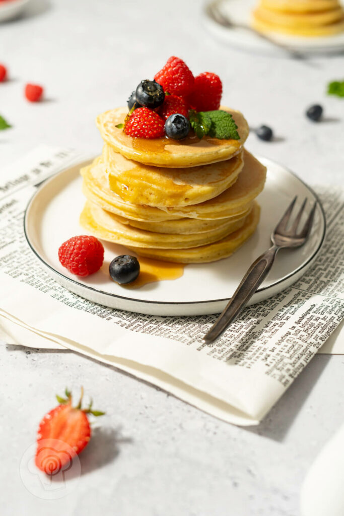 American Pancakes mit Ahornsirup und frischen Früchten gestapelt