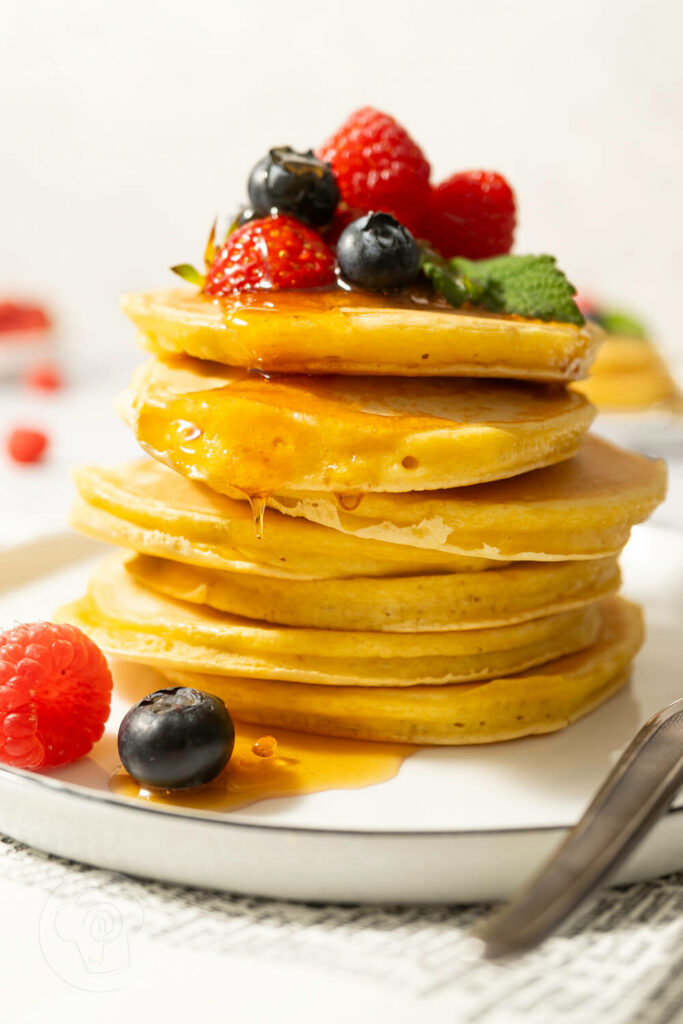 American Pancakes mit Ahornsirup und frischen Früchten gestapelt