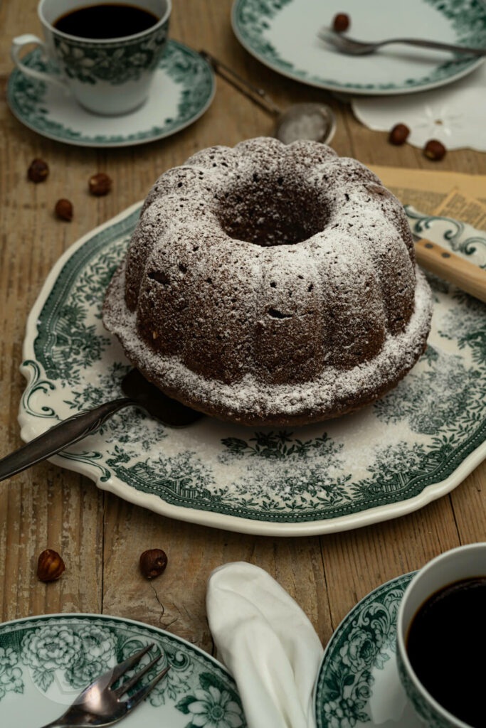 Nuss-Gugelhupf saftig auf einer Kuchenplatte.