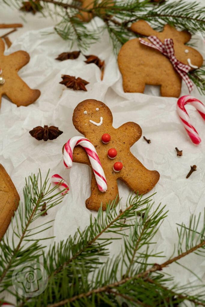 Pfefferkuchen-Männchen auf Seidenpapier mit Zuckerstangen und Gewürzen